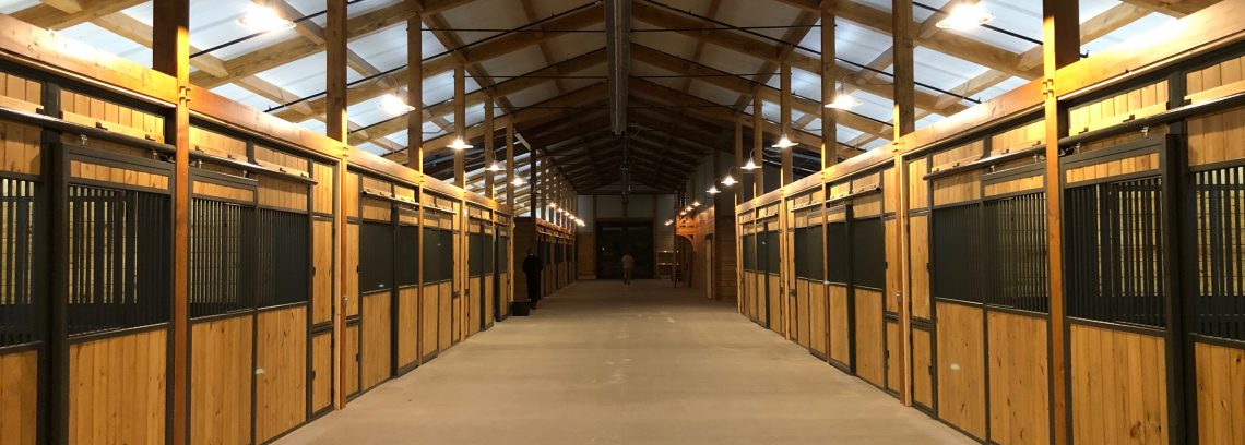 Interior of barn looking down aisle with horse stalls on both sides